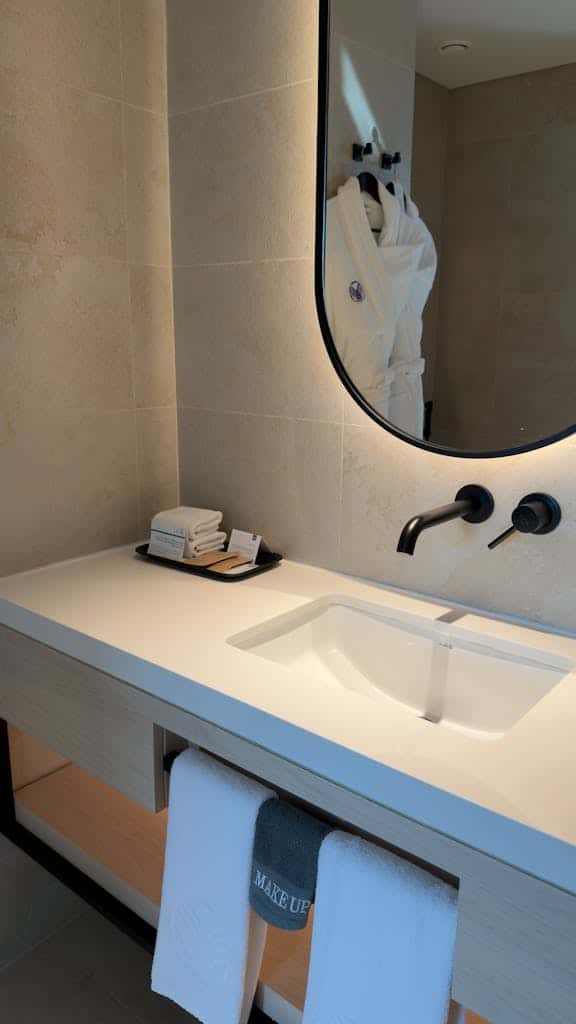 Elegant bathroom interior with modern sink, mirror, and plush towels in a luxurious hotel setting.